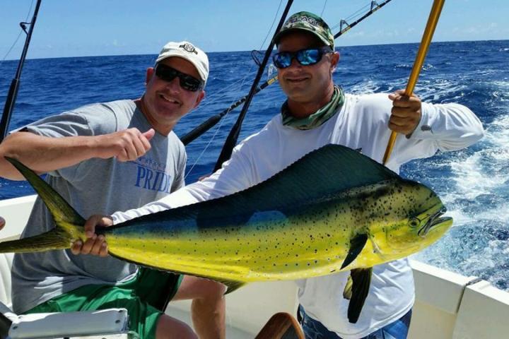 a man holding a fish on a boat in a body of water